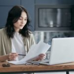 Person on the phone reviewing Medicaid mental health coverage paperwork at a kitchen table